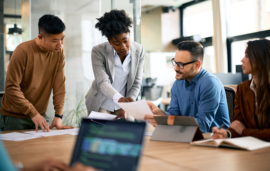 Group of diverse business professionals collaborating and discussing paperwork in a modern office setting