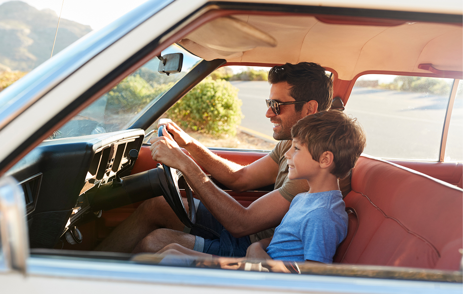Smiling father and son driving together in a classic car