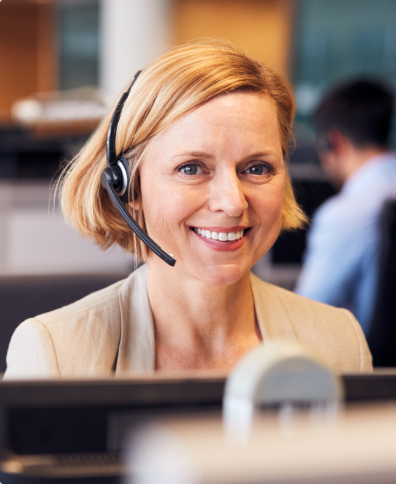 Smiling female customer support agent wearing a headset in an office setting