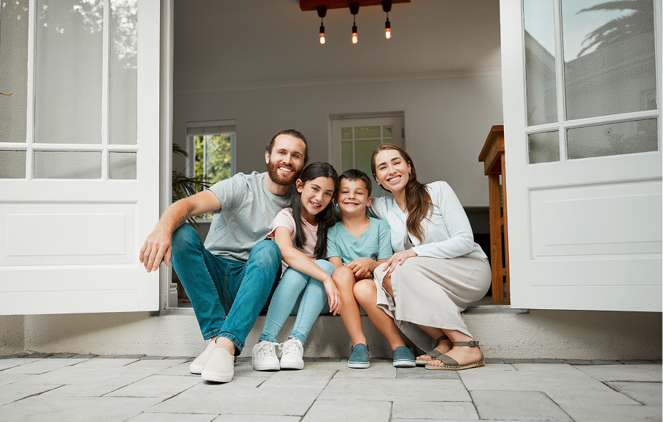 Happy smiling family of four sitting together in the doorway of their home