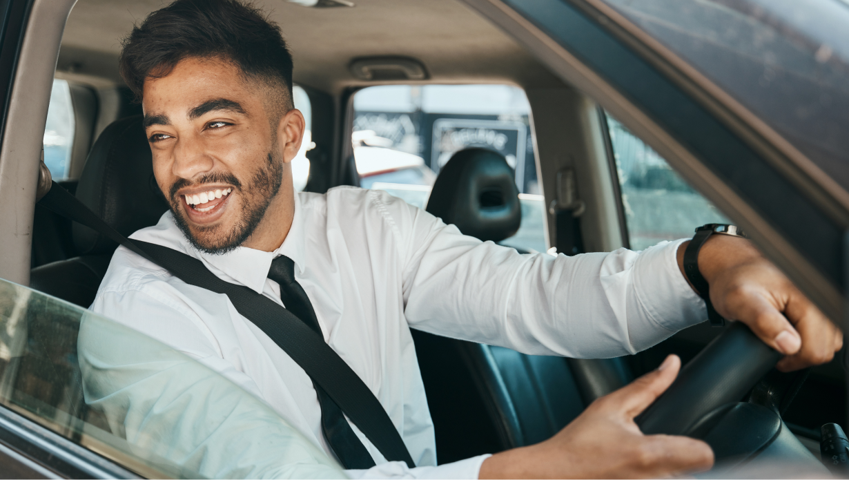 Smiling man driving car in city during daytime